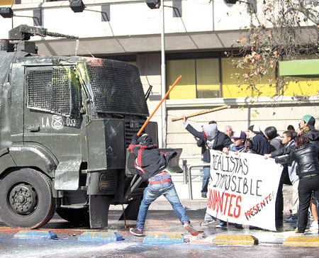 Estudiantes chilenos cargan contra un camión hidrante en una calle de Santiago, en la protesta del jueves pasado. 