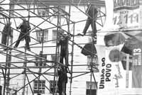 Varias personas se suben a una estructura tubular para colgar los carteles de la “Unión del Pueblo”.