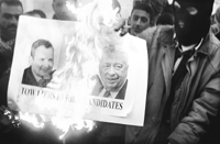 Un palestino enmascarado quema las imágenes de los candidatos israelíes.