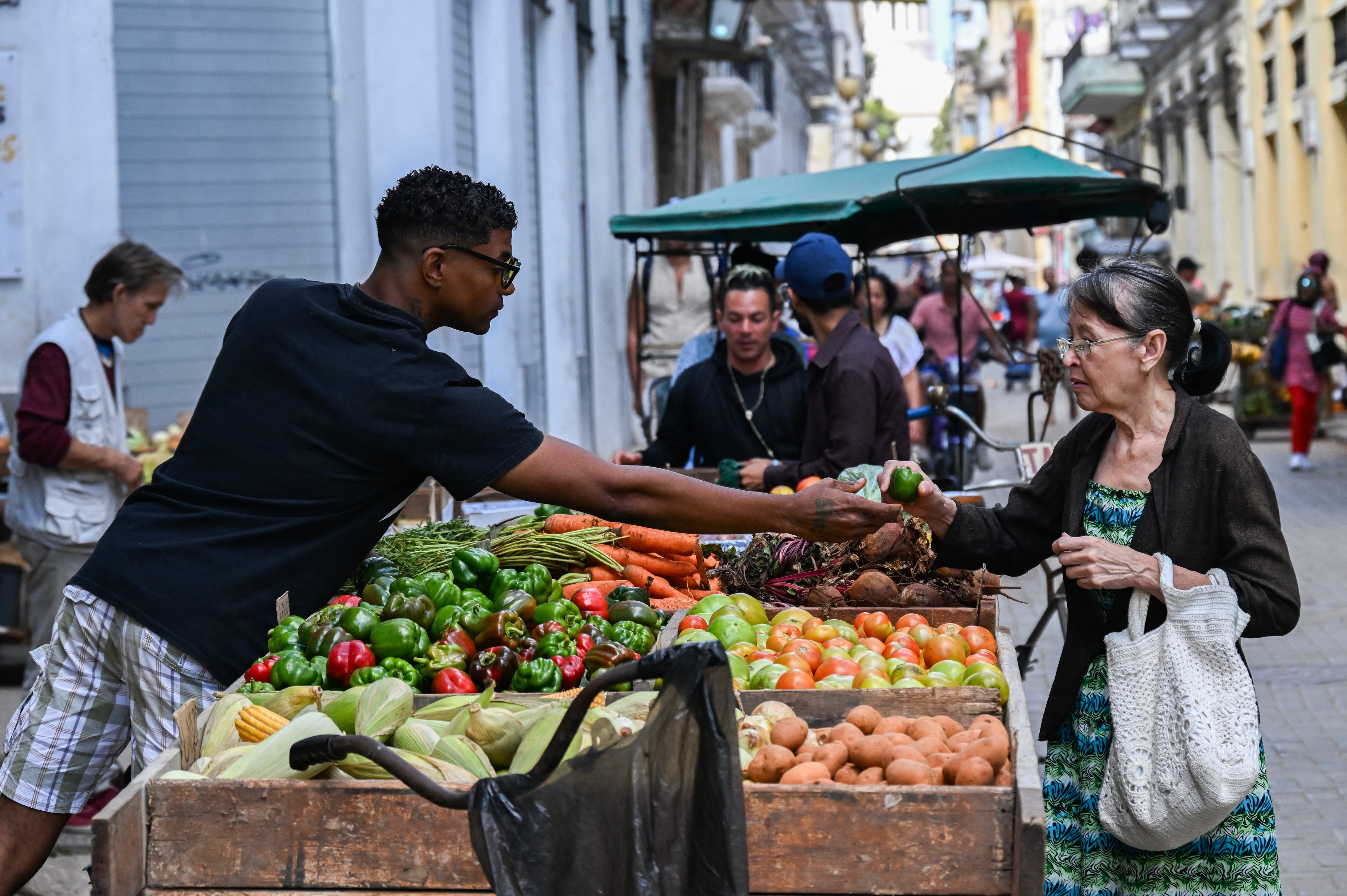 A woman buys vegetables from a street vendor on a street in Havana on May 4, 2026. (Photo by YAMIL LAGE / AFP)