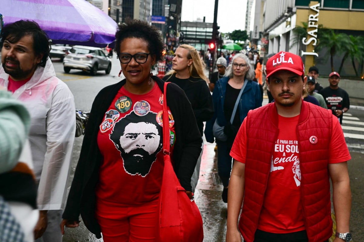 People walk along a street wearing a T-shirt bearing the image of Brazil's President and Workers' Party (PT) re-election candidate Luiz Inacio