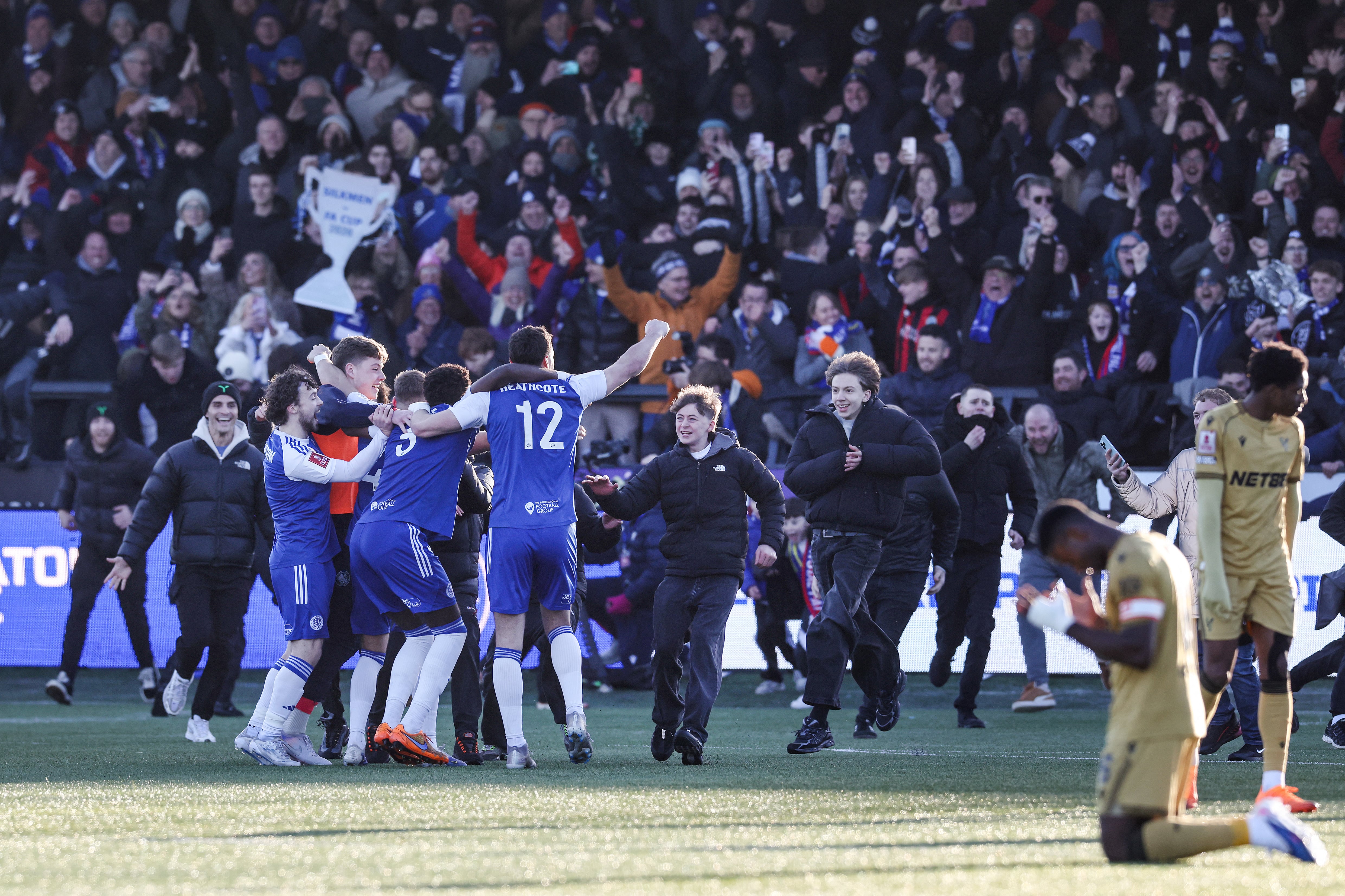 Macclesfield supporters (C) storm the pitch to celebrate the team's victory with players (L) at the end of the English FA Cup third round football match between Macclesfield Town and Crystal Palace at Leasing.com Stadium, Moss Rose in Macclesfield, northern England on January 10, 2026. (Photo by Darren Staples / AFP) / RESTRICTED TO EDITORIAL USE. NO USE WITH UNAUTHORIZED AUDIO, VIDEO, DATA, FIXTURE LISTS, CLUB/LEAGUE LOGOS OR 'LIVE' SERVICES. ONLINE IN-MATCH USE LIMITED TO 120 IMAGES. AN ADDITIONAL 40 IMAGES MAY BE USED IN EXTRA TIME. NO VIDEO EMULATION. SOCIAL MEDIA IN-MATCH USE LIMITED TO 120 IMAGES. AN ADDITIONAL 40 IMAGES MAY BE USED IN EXTRA TIME. NO USE IN BETTING PUBLICATIONS, GAMES OR SINGLE CLUB/LEAGUE/PLAYER PUBLICATIONS. /
