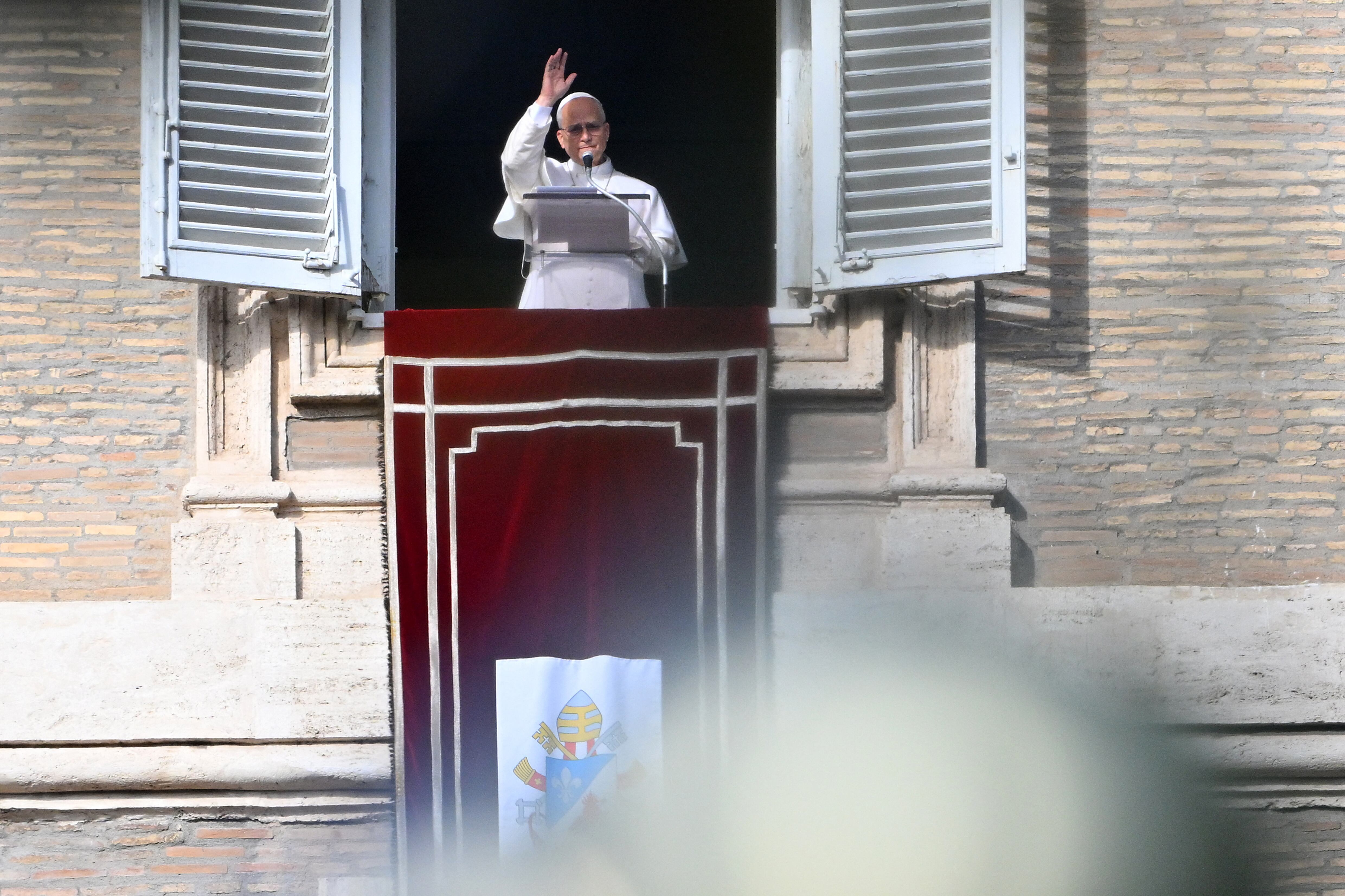 Pope Leo XIV blesses the crowd from a window of the apostolic palace overlooking St. Peter's Square during the Angelus prayer in The Vatican on December 21, 2025. (Photo by Andreas SOLARO / AFP)