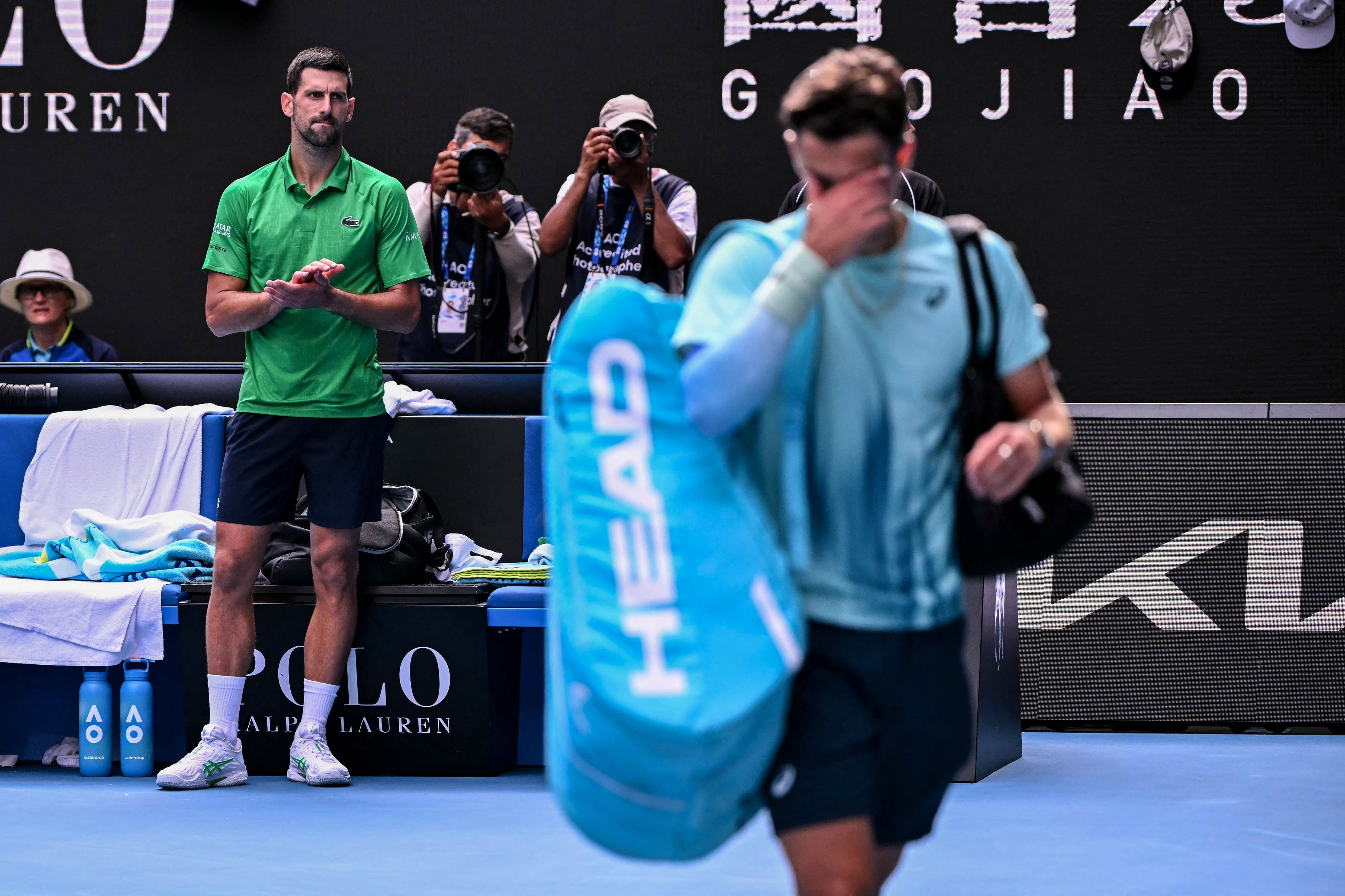 Serbia's Novak Djokovic (L) applauds as Italy's Lorenzo Musetti (R) walks off the court after retiring from their men's singles quarter-final match on day eleven of the Australian Open tennis tournament in Melbourne on January 28, 2026. (Photo by WILLIAM WEST / AFP) / -- IMAGE RESTRICTED TO EDITORIAL USE - STRICTLY NO COMMERCIAL USE --