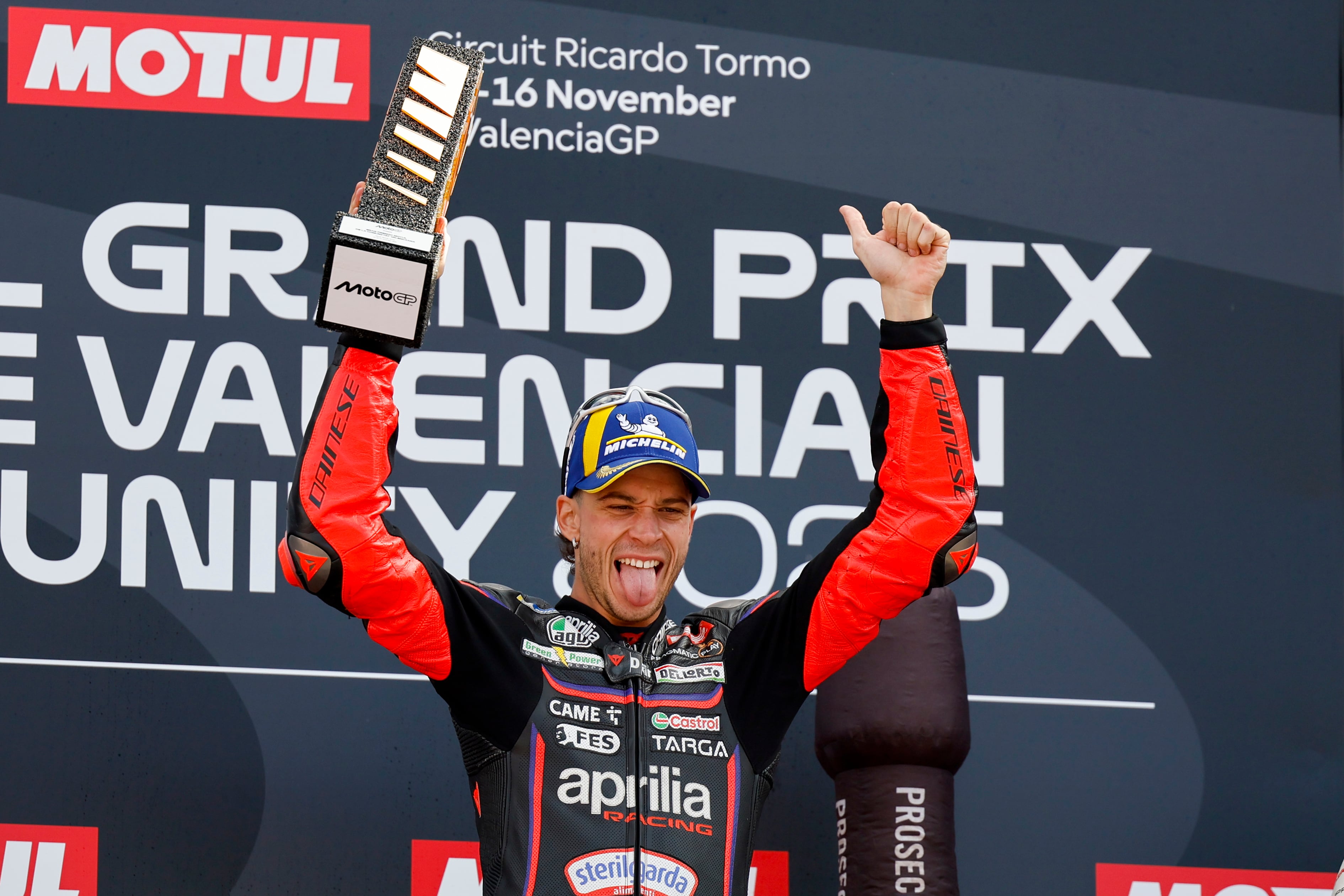 GRAFCVA695. CHESTE (VALENCIA), 16/11/2025.- El piloto italiano en la categoría de Moto GP, Marco Bezzecchi, celebra su victoria en el podio junto a su compatriota, Fabio Di Giannantonio (d), tras la carrera del Gran Premio de la Comunitat Valencia de MotoGP que se disputa este domingo en el Circuito Ricardo Tormo. EFE/Ana Escobar