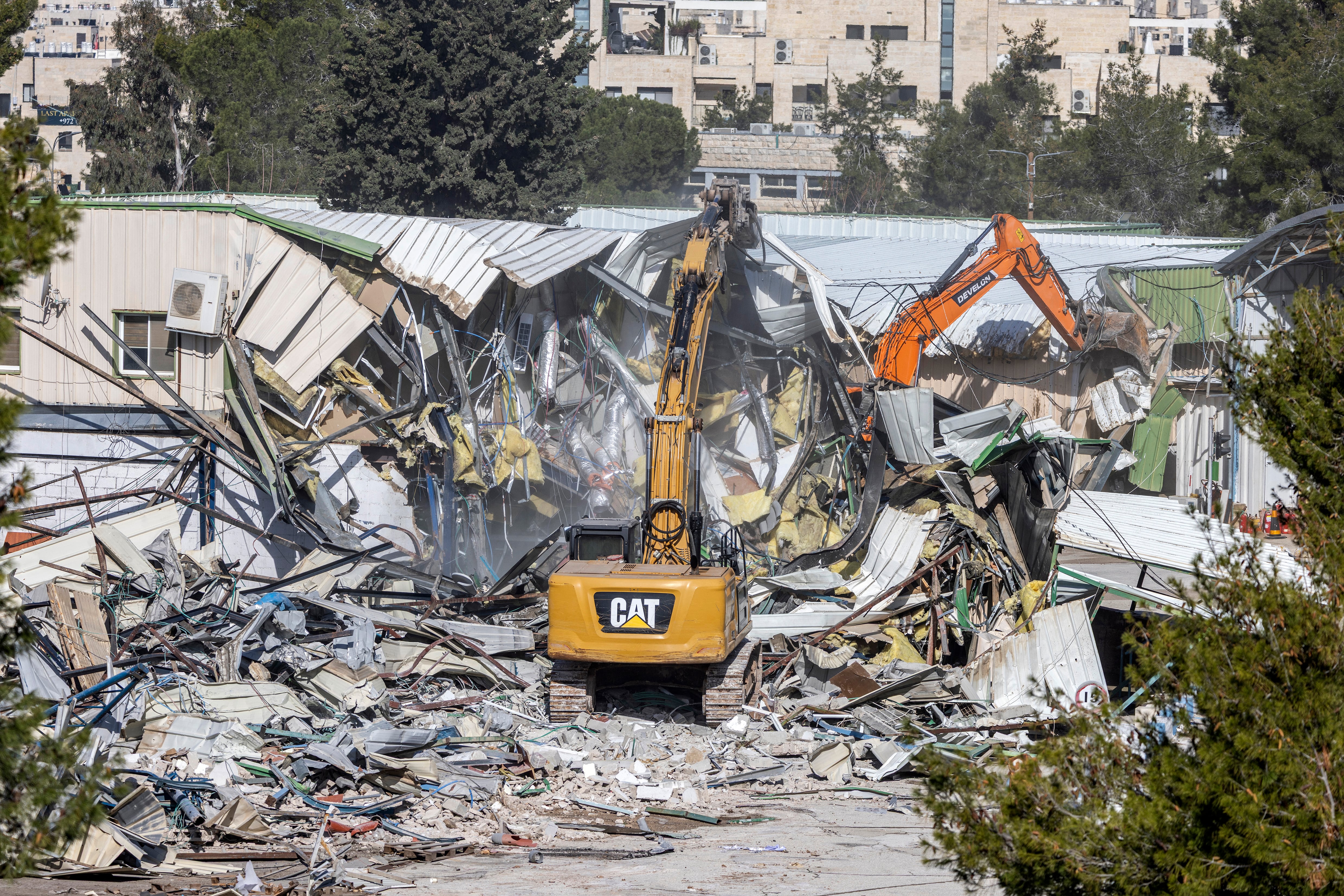 A photograph shows machinery demolishing a structure inside the headquarters of the United Nations Relief and Works Agency (UNRWA) in the Sheikh Jarrah neighbourhood of Israeli-annexed east Jerusalem on January 20, 2026. Israeli bulldozers began demolitions at the headquarters of the UN agency for Palestinian refugees in east Jerusalem on January 20, in what the organisation called an "unprecedented attack". The compound in Israeli-annexed east Jerusalem has been empty of UNRWA staff since January 2025, when a law banning its operations took effect after a months-long battle over its work in the Gaza Strip. (Photo by ILIA YEFIMOVICH / AFP)