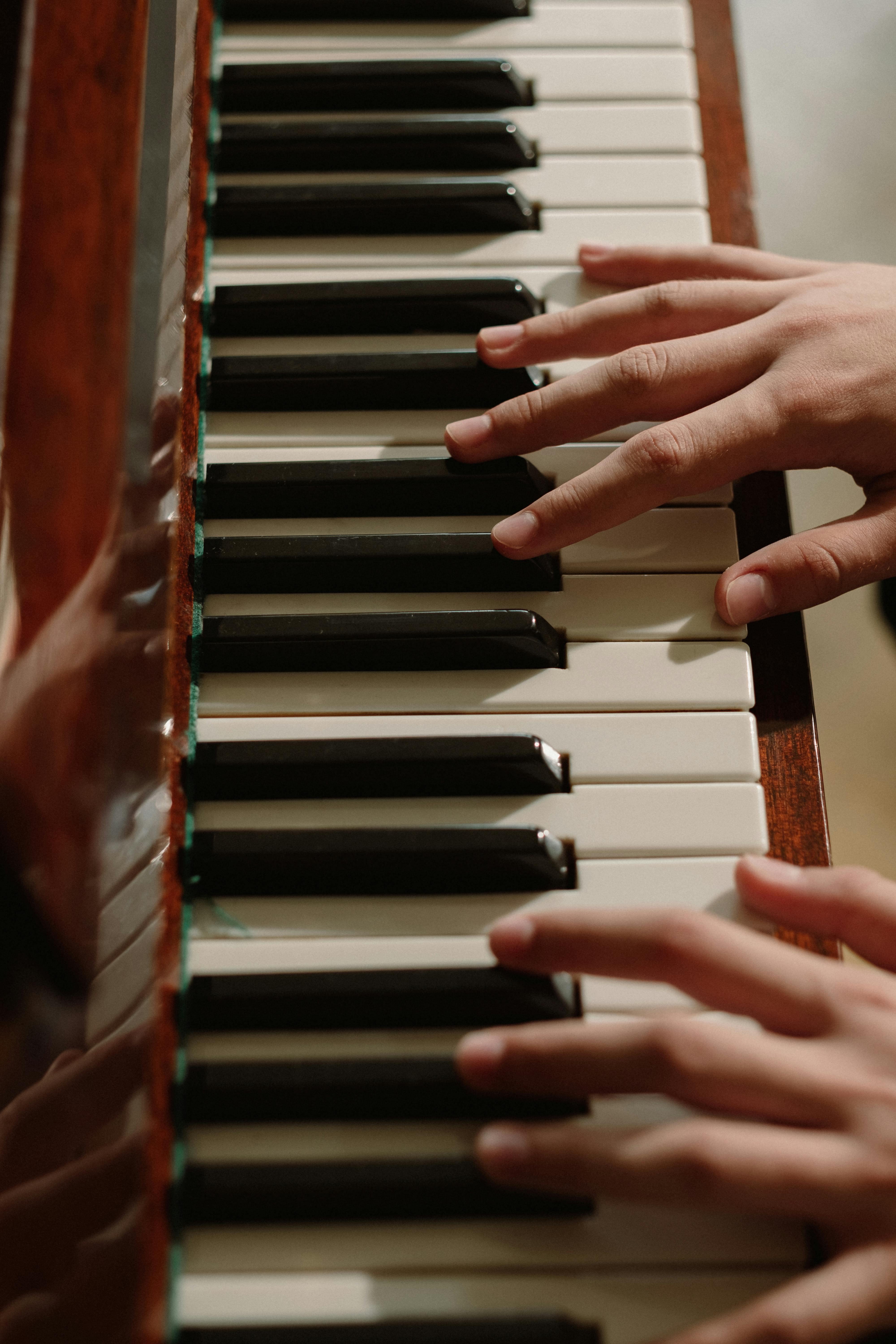Las manos de una niña posadas sobre un teclado de piano.