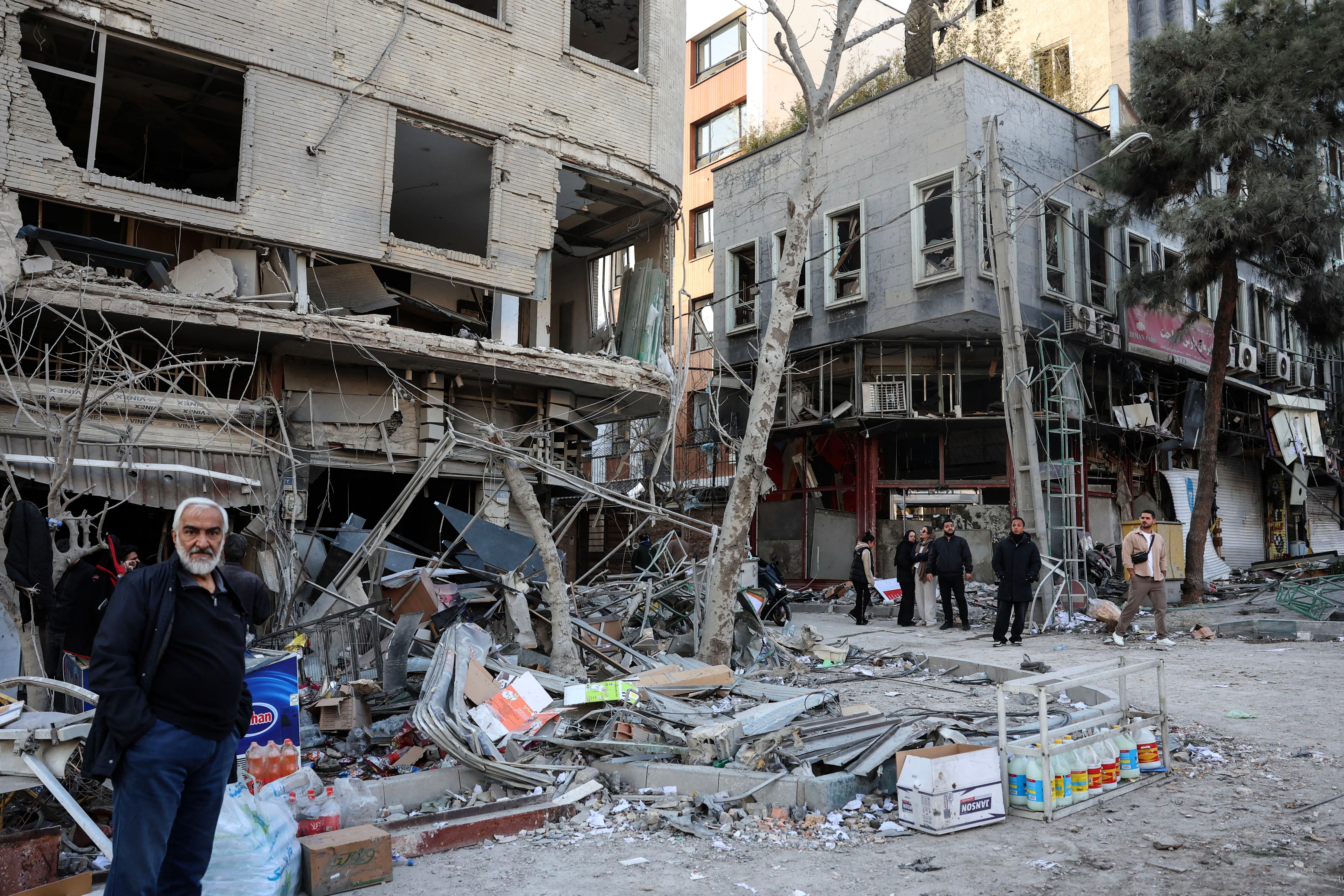 Residents stand on a street beside damaged residential buildings near Niloufar square in Tehran during the ongoing joint US-Israeli military campaign on Iran on March 2, 2026. The United States and Israel launched strikes against Iran on February 28, killing Iran's supreme leader and top military leaders, prompting authorities to retaliate with strikes on Israel and across the Gulf. (Photo by AFP)