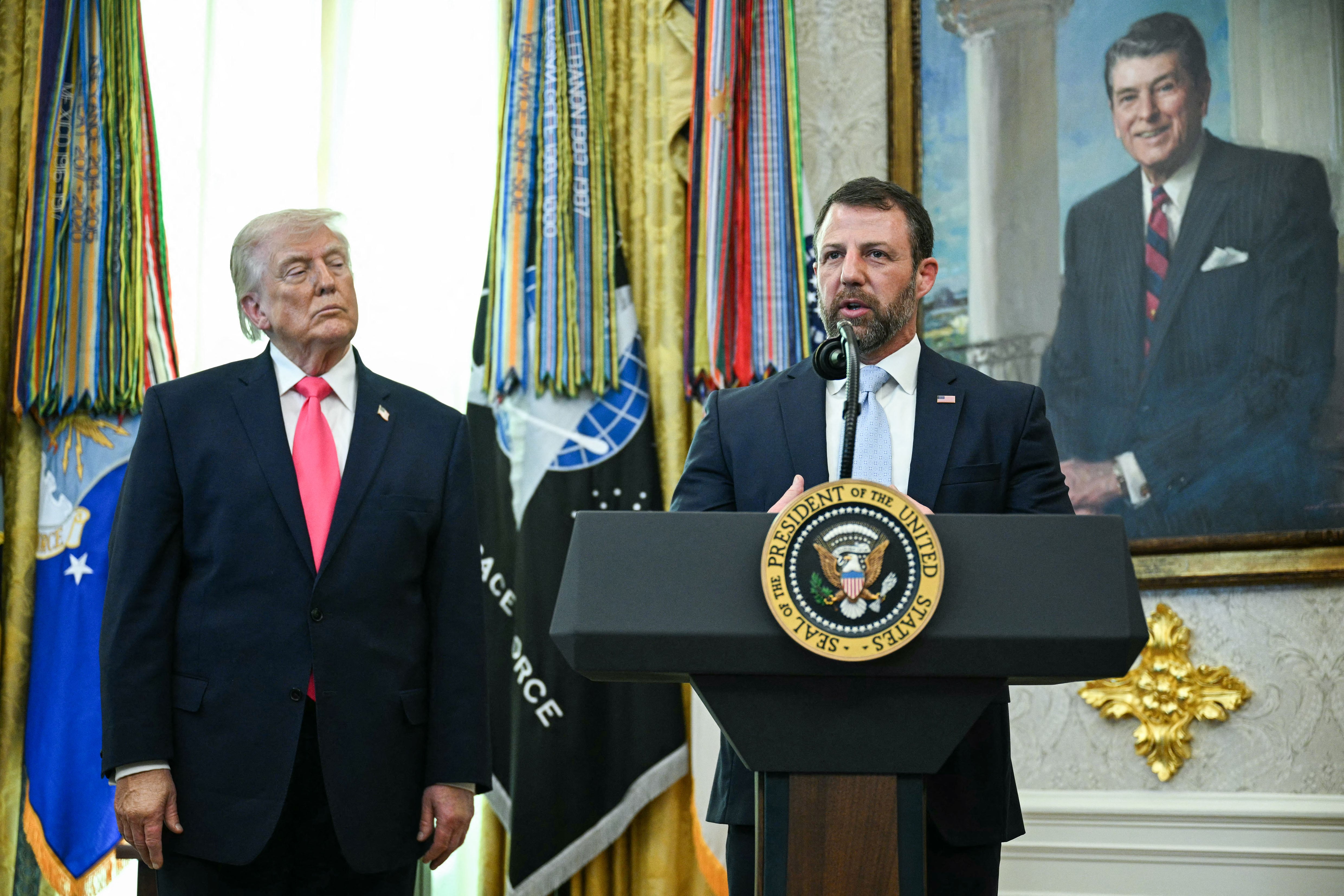US President Donald Trump looks on as newly sworn in Secretary of Homeland Security Markwayne Mullin speaks in the Oval Office of the White House in Washington, DC, on March 24, 2026. The US Senate on Monday confirmed Mullin as the new chief of the Department of Homeland Security (DHS), the agency reeling from a partial government shutdown as it works to enforce President Donald Trump's immigration crackdown. (Photo by Jim WATSON / AFP)
