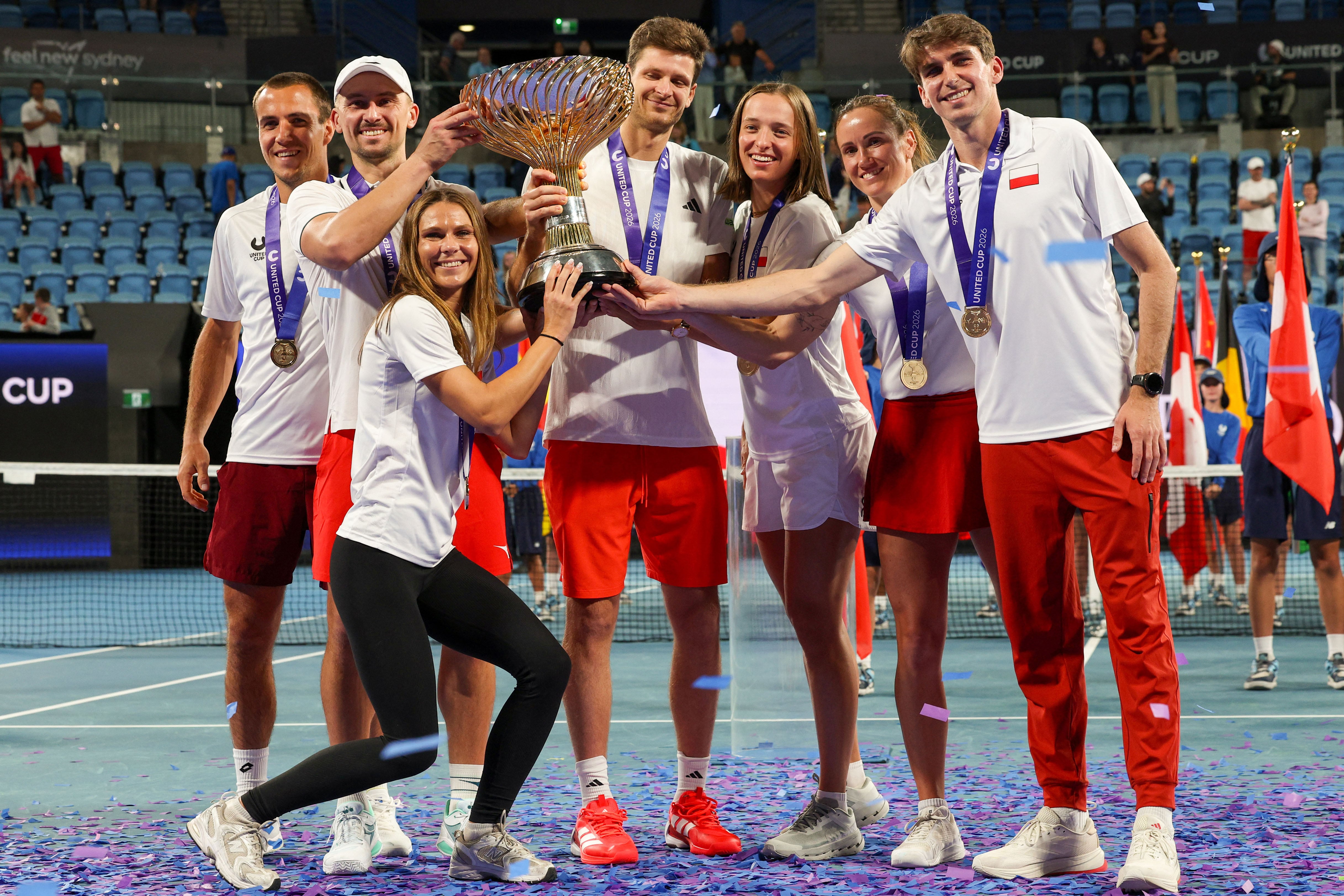Team Poland pose with the trophy after defeating team Switzerland in the final event at the United Cup tennis tournament in Sydney on January 12, 2026. (Photo by Izhar KHAN / AFP) / --IMAGE RESTRICTED TO EDITORIAL USE - STRICTLY NO COMMERCIAL USE--