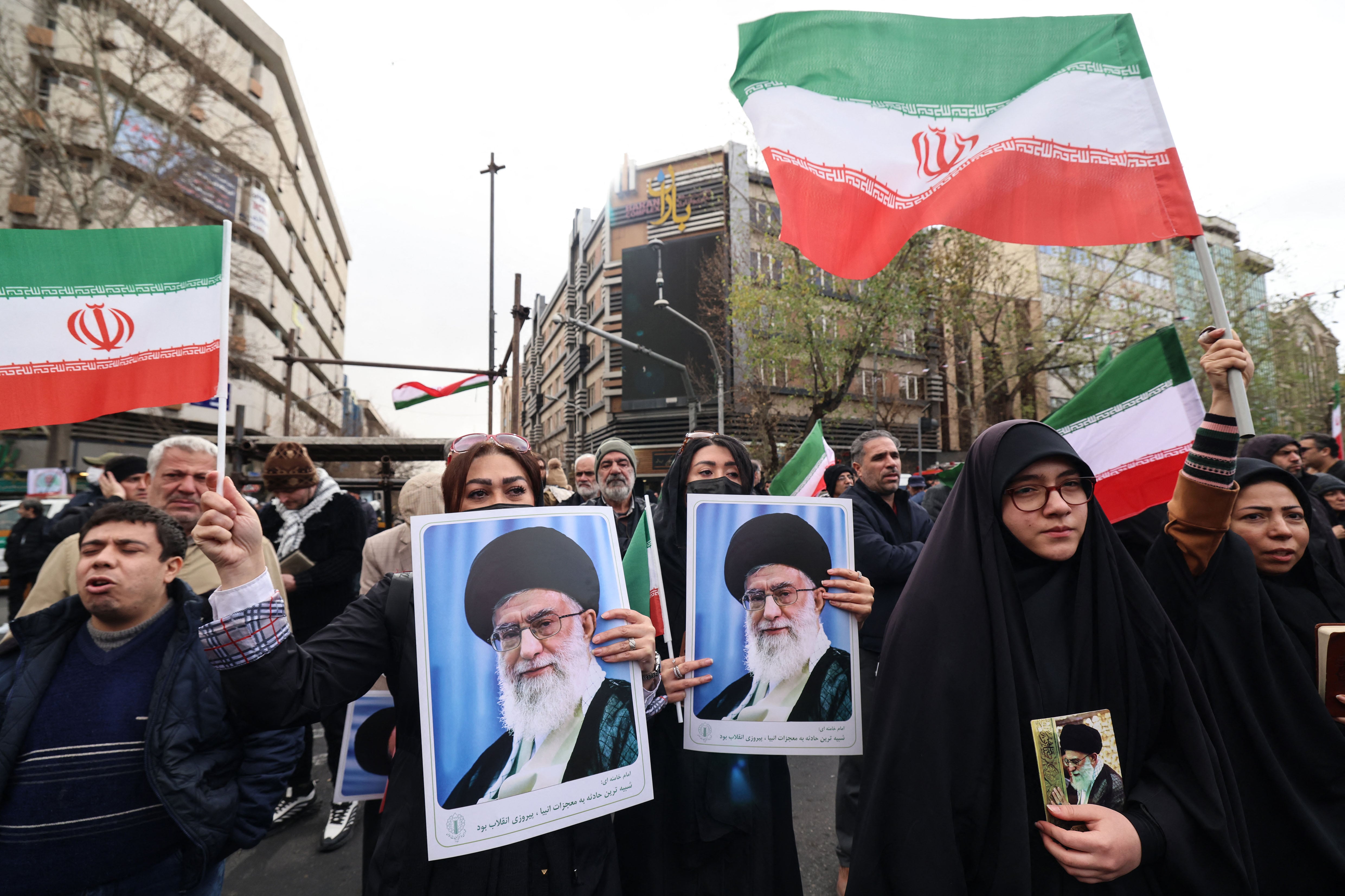 Iranian women hold portraits of Iran’s Supreme Leader Ayatollah Ali Khamenei during the funerals of security forces personnel killed in recent protests in Tehran on January 14, 2026. A funeral ceremony began in Tehran on January 14, 2026 for over 100 members of the security forces and other "martyrs" killed in the wave of protests that has rocked the Islamic republic, state television said. (Photo by ATTA KENARE / AFP)