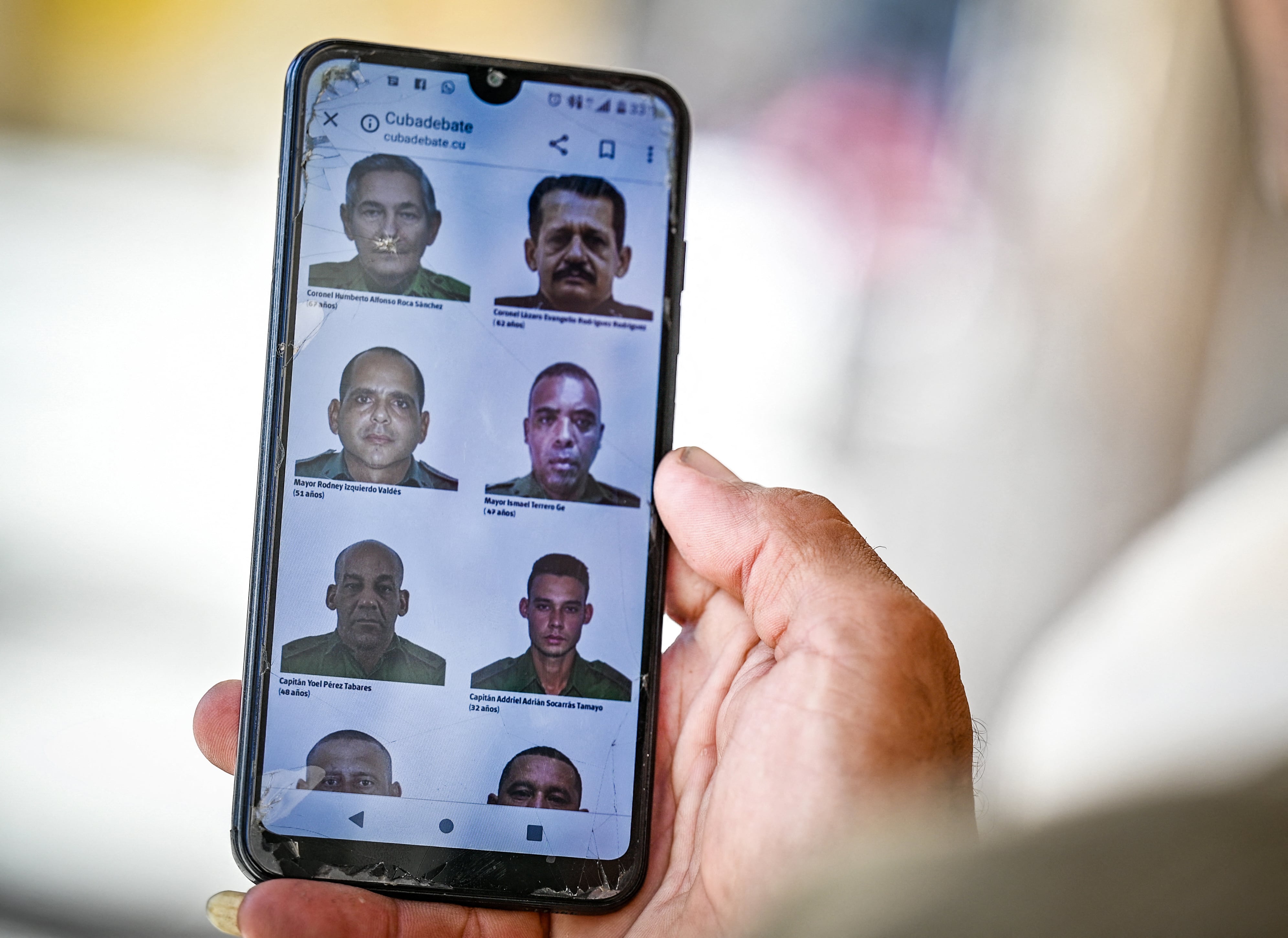 A man in Havana goes through the official website of the Cuban government cubadebate.cu on his mobile phone, where images of some of the 32 Cuban officers and soldiers killed during the US military intervention in Venezuela are displayed, on January 6, 2026. US forces killed 55 Venezuelan and Cuban military personnel during their stunning raid to capture Nicolas Maduro, tolls published by Caracas and Havana showed on January 6. Cuba, which had already announced that 32 members of its armed forces and interior ministry security personnel assigned to duties in Caracas were killed in the raids, also listed its dead. (Photo by Adalberto ROQUE / AFP)
