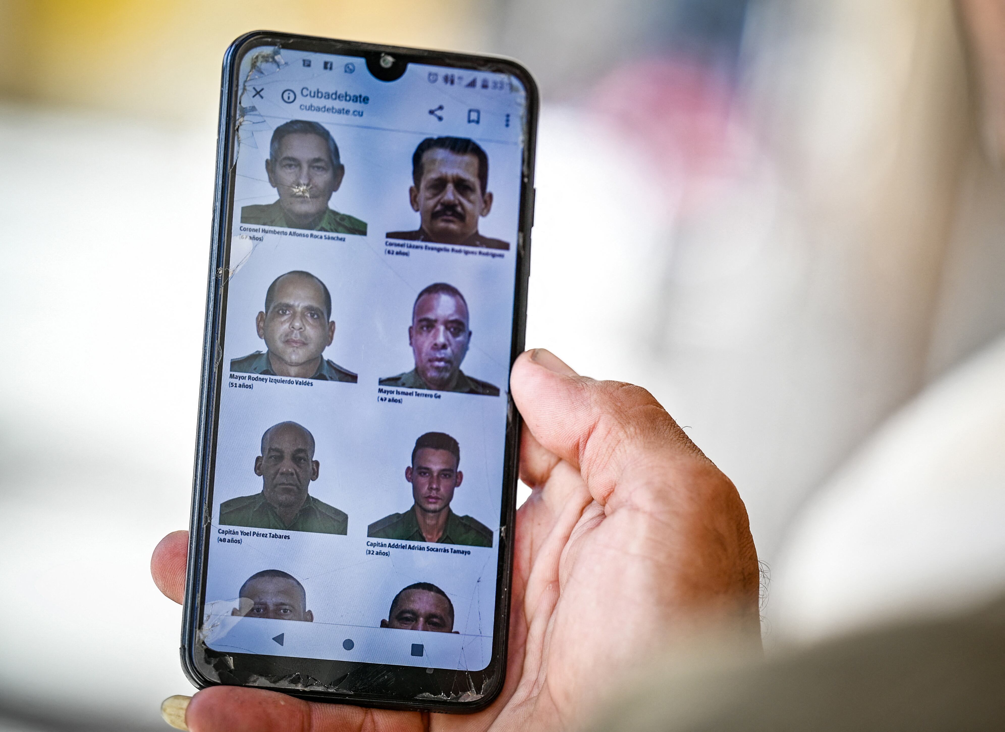 A man in Havana goes through the official website of the Cuban government cubadebate.cu on his mobile phone, where images of some of the 32 Cuban officers and soldiers killed during the US military intervention in Venezuela are displayed, on January 6, 2026. US forces killed 55 Venezuelan and Cuban military personnel during their stunning raid to capture Nicolas Maduro, tolls published by Caracas and Havana showed on January 6. Cuba, which had already announced that 32 members of its armed forces and interior ministry security personnel assigned to duties in Caracas were killed in the raids, also listed its dead. (Photo by Adalberto ROQUE / AFP)