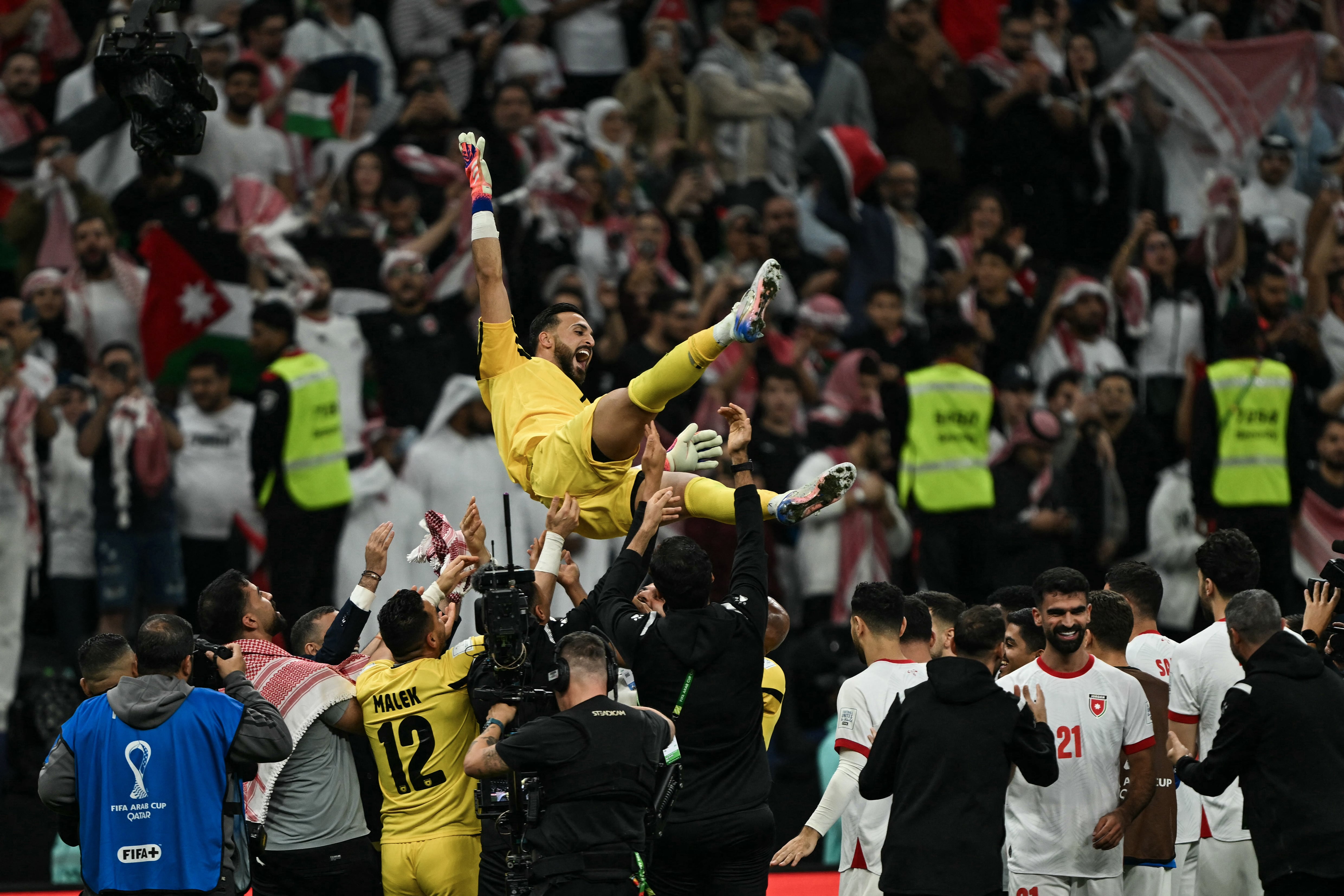Jordan's team members celebrate with goalkeeper #1 Yazeed Abulaila at the end of the FIFA Arab Cup 2025 semi-final football match between Saudi Arabia and Jordan at the Al-Bayt Stadium in Al-Khor on December 15, 2025. (Photo by Mahmud HAMS / AFP)