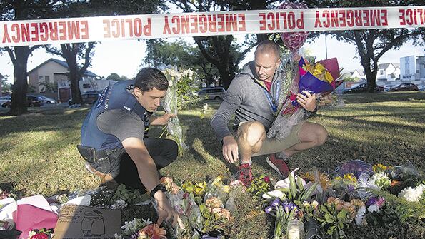 Policías llevan flores al altar improvisado frente a la mezquita de Linwood en Christchurch, Nueva Zelanda.