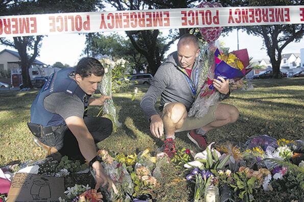 Policías llevan flores al altar improvisado frente a la mezquita de Linwood en Christchurch, Nueva Zelanda.