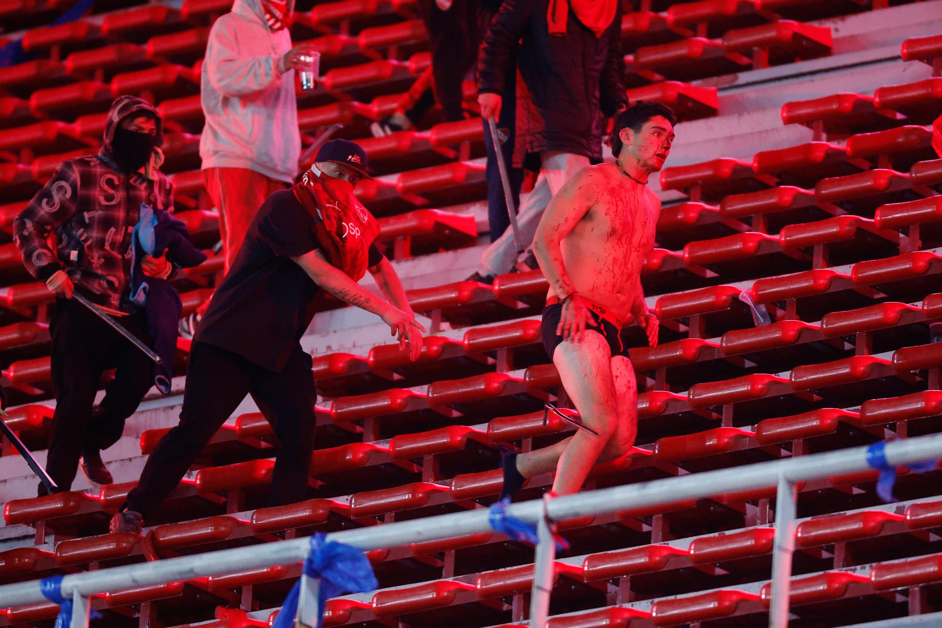 Un hincha chileno desnudo y ensangrentado. Atrás quieren seguir la cacería