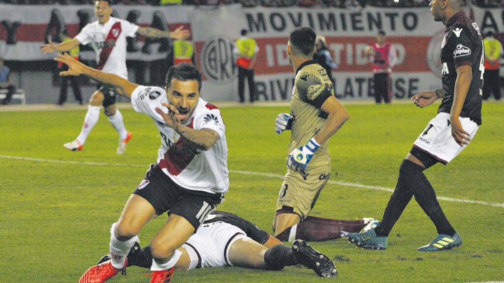 Scocco festeja la apertura del marcador, con Andrada arrodillado en el pasto.