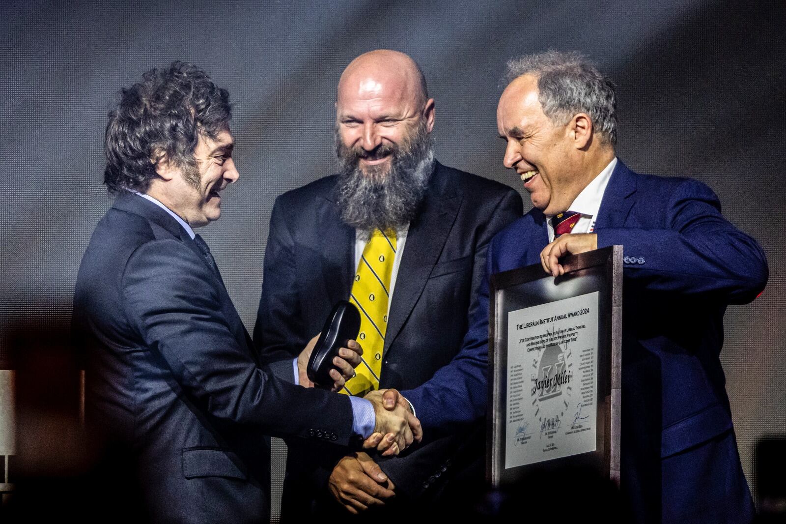 Milei sonríe cuando recibe el diploma. 