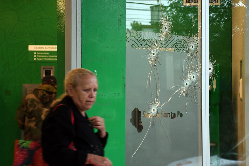 Una clienta sale de la sucursal que ayer mostrada las huellas del ataque.