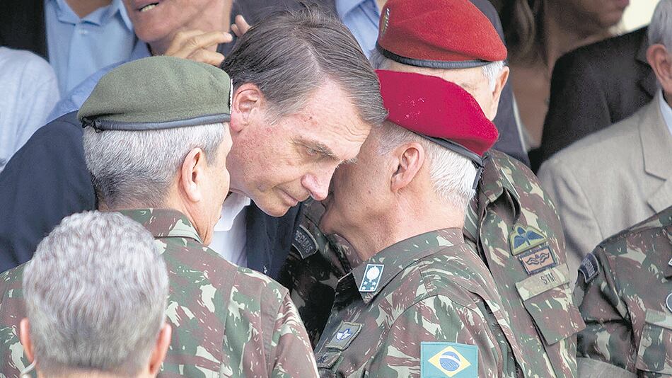 El general del Ejército Baptista Pereira le habla al oído a Bolsonaro durante una ceremonia en Río de Janeiro.