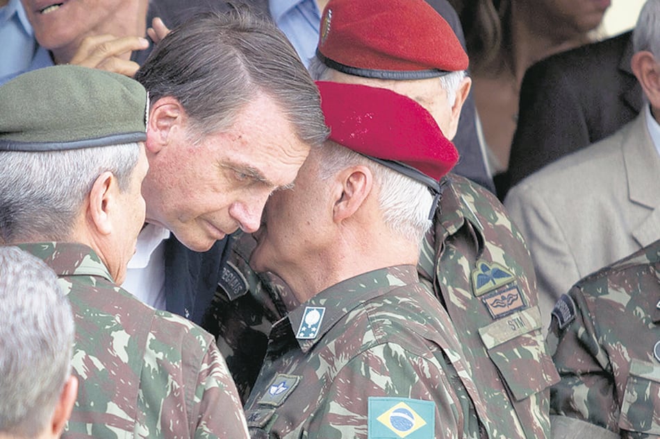 El general del Ejército Baptista Pereira le habla al oído a Bolsonaro durante una ceremonia en Río de Janeiro.