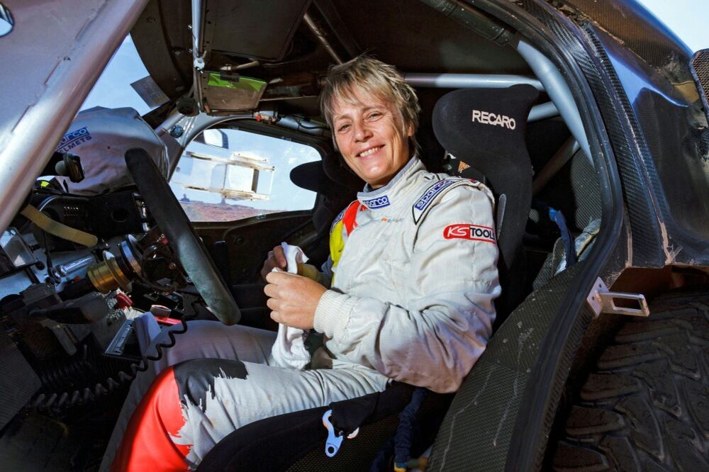 Kleinschmidt sonríe arriba de una auto de rally.