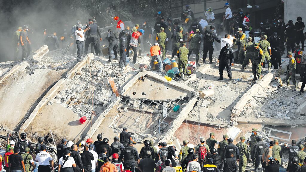 Los rescatistas, con picos, golpean sobre los bloques de hormigón para abrir vías de respiración e intentar localizar víctimas.