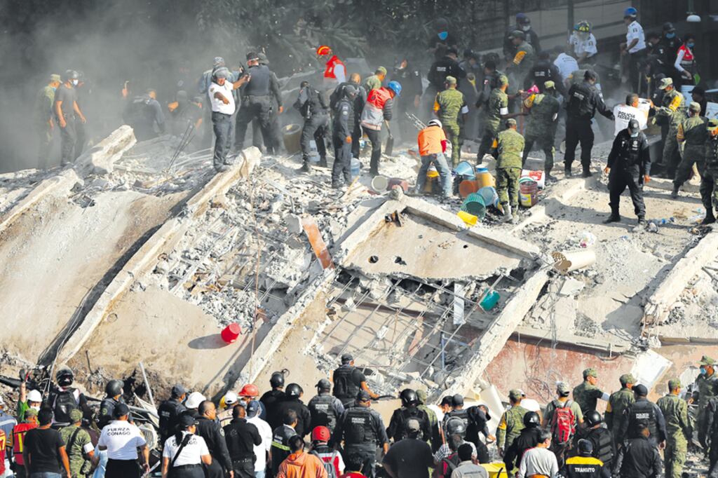 Los rescatistas, con picos, golpean sobre los bloques de hormigón para abrir vías de respiración e intentar localizar víctimas.