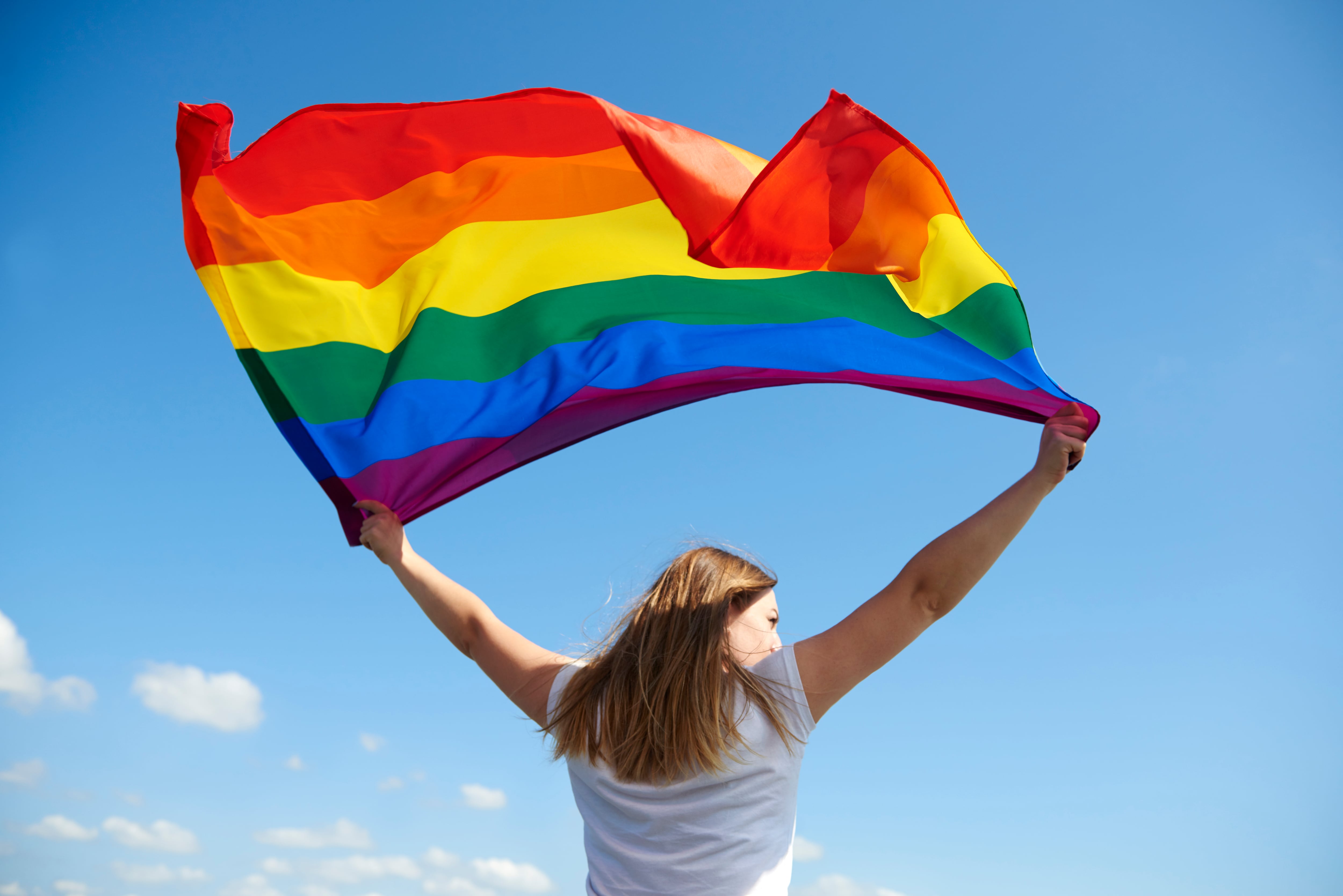 Una mujer sostiene la bandera del orgullo. Imagen: Freepik