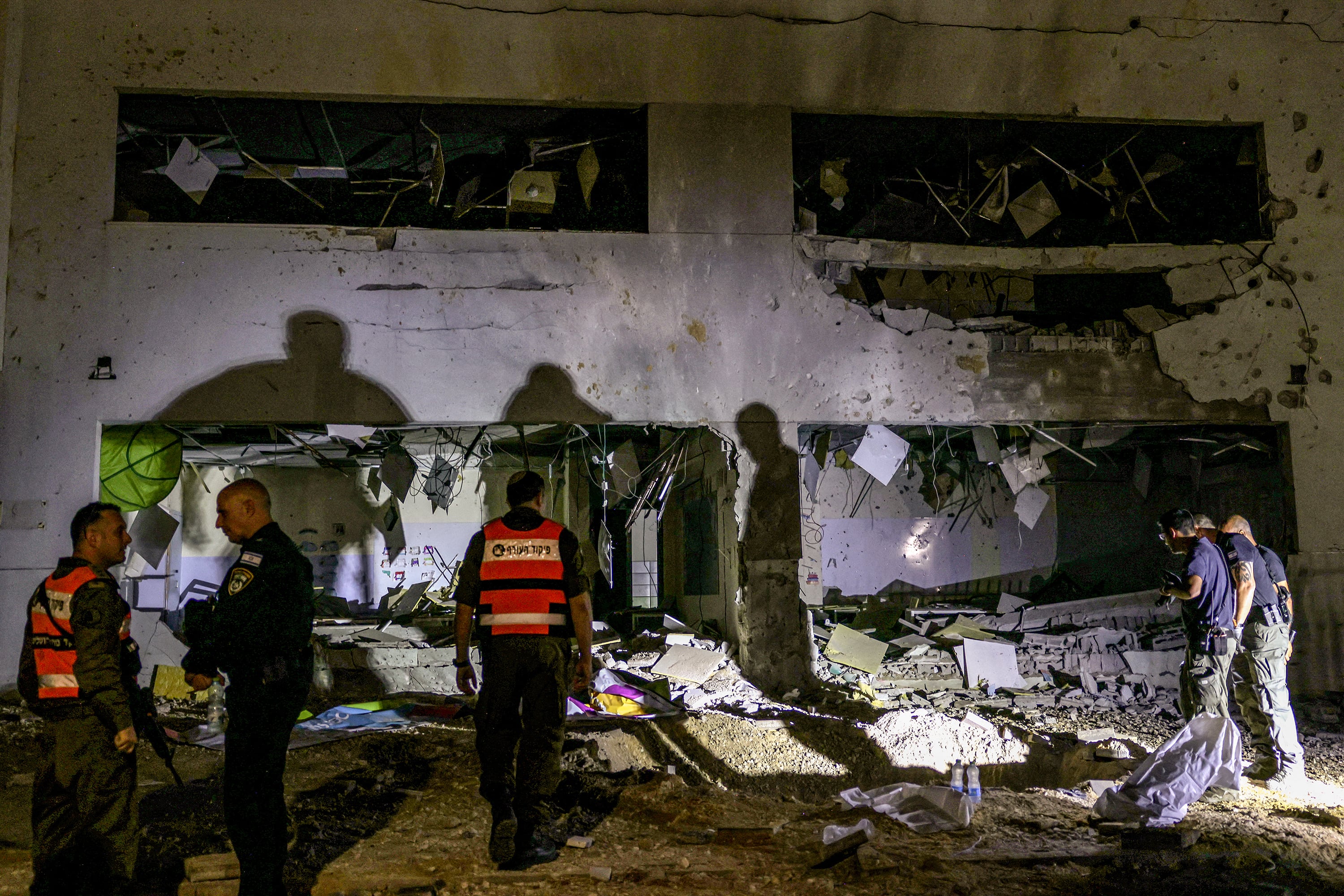 Fuerzas de seguridad israelíes inspeccionan un crater que dejó un misil iraní en la ciudad de Gedera.