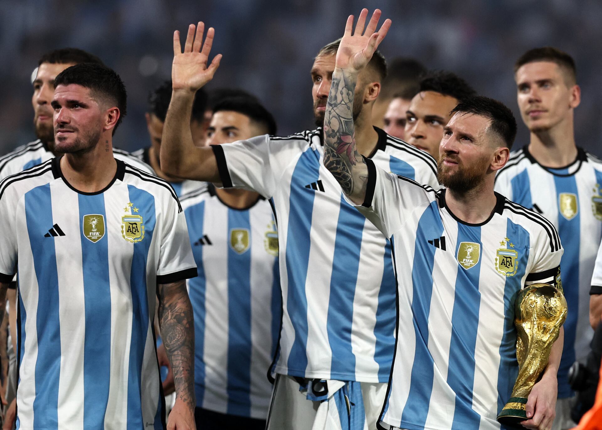 Lionel Messi sostiene la copa del Mundo y la selección argentina saluda a los hinchas en medio de la fiesta. 