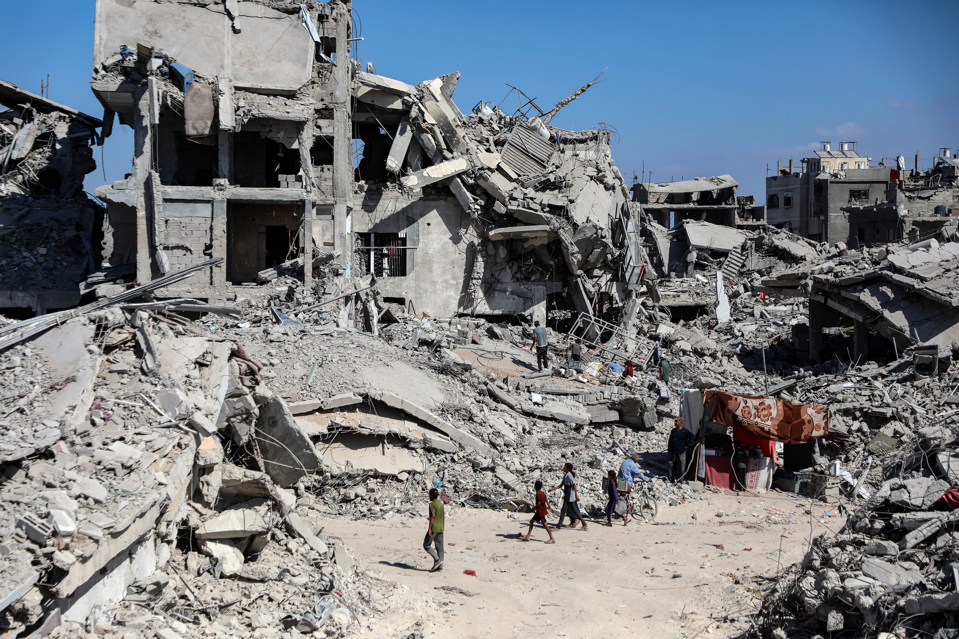 Un grupo de palestinos circula entre edificios destruidos en el campamento de refugiados de Jabalia