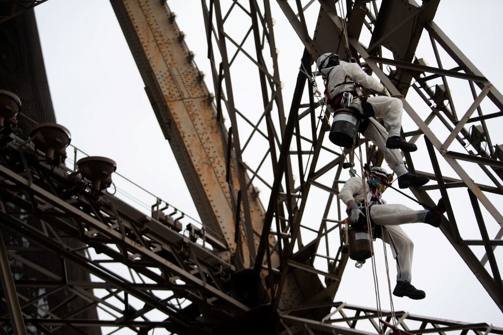 Los pintores que trabajan en altura para repitar la Torre Eiffel.