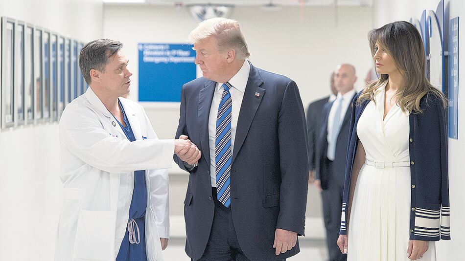 Trump saluda a uno de los médicos mientras Melania escucha.