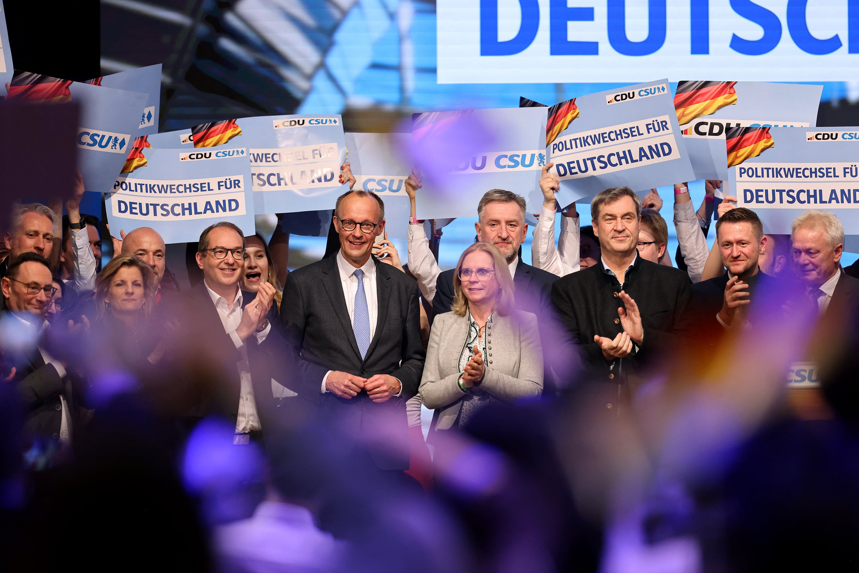 Merz (centro, izq.) sonríe durante el cierre de campaña en Munich.