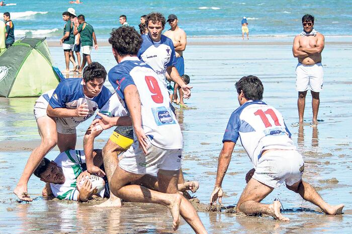 Los jugadores de beach rugby, peleando por quedarse con la ovalada chapoteando en el agua.
