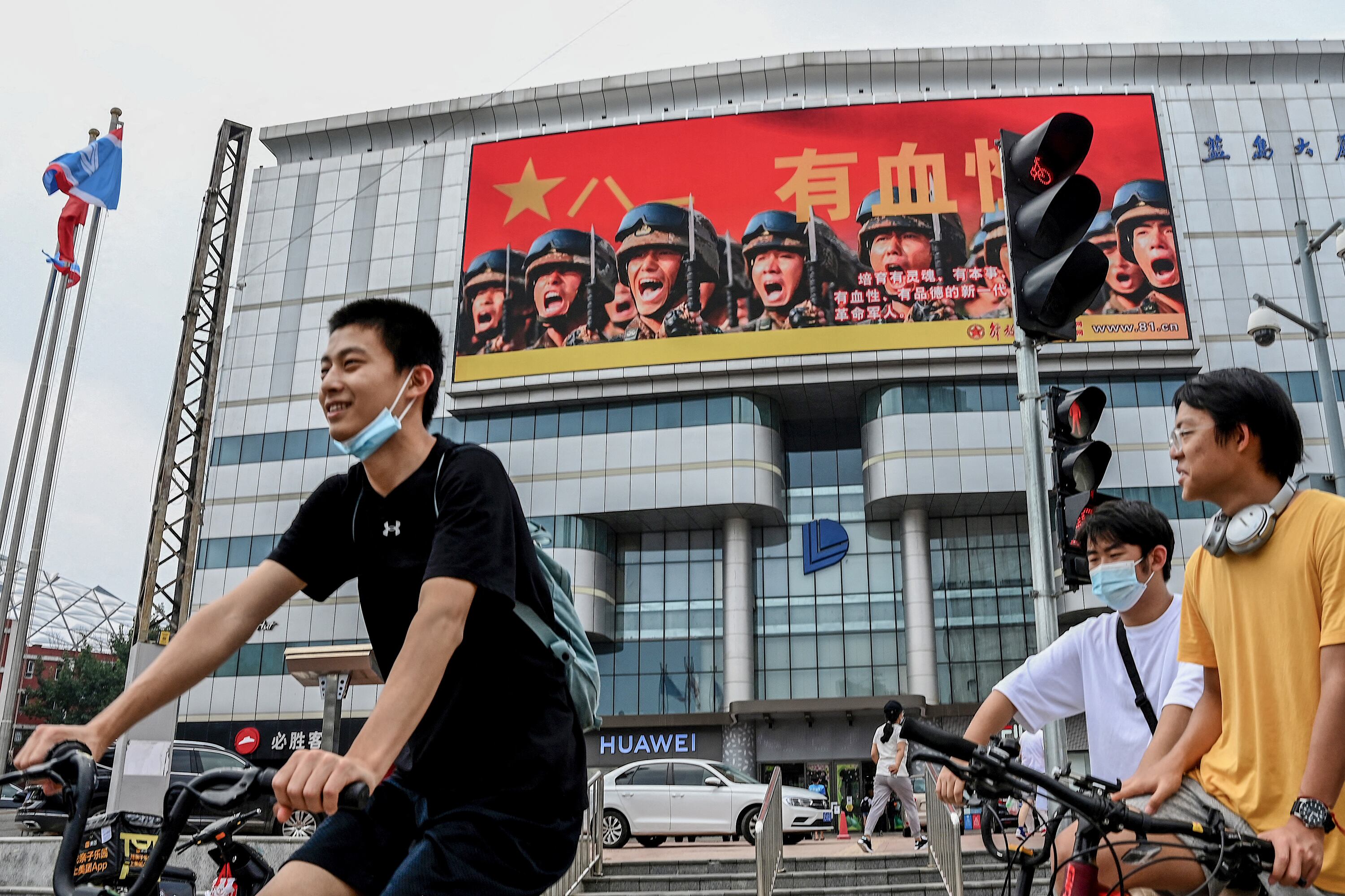 Ciclistas pasan delante de una publicidad del ejército chino en Beijing.