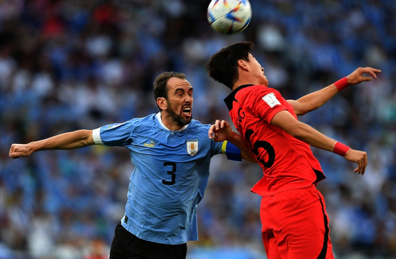 Diego Godín lucha por la pelota con un jugador coreano