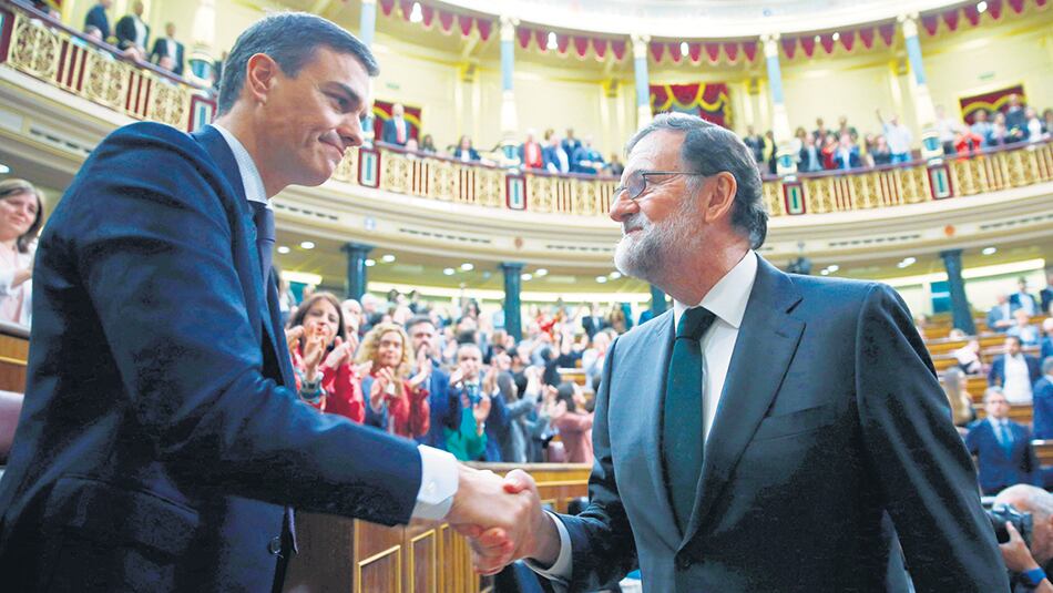 Pedro Sánchez recibe el saludo de su antecesor, Mariano Rajoy, instantes después de su investidura, ayer, en el Congreso español.