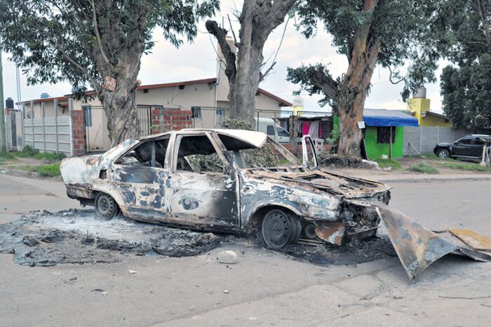 Uno de los autos quemados durante el enfrentamiento. A unos metros encontraron un cadáver quemado.