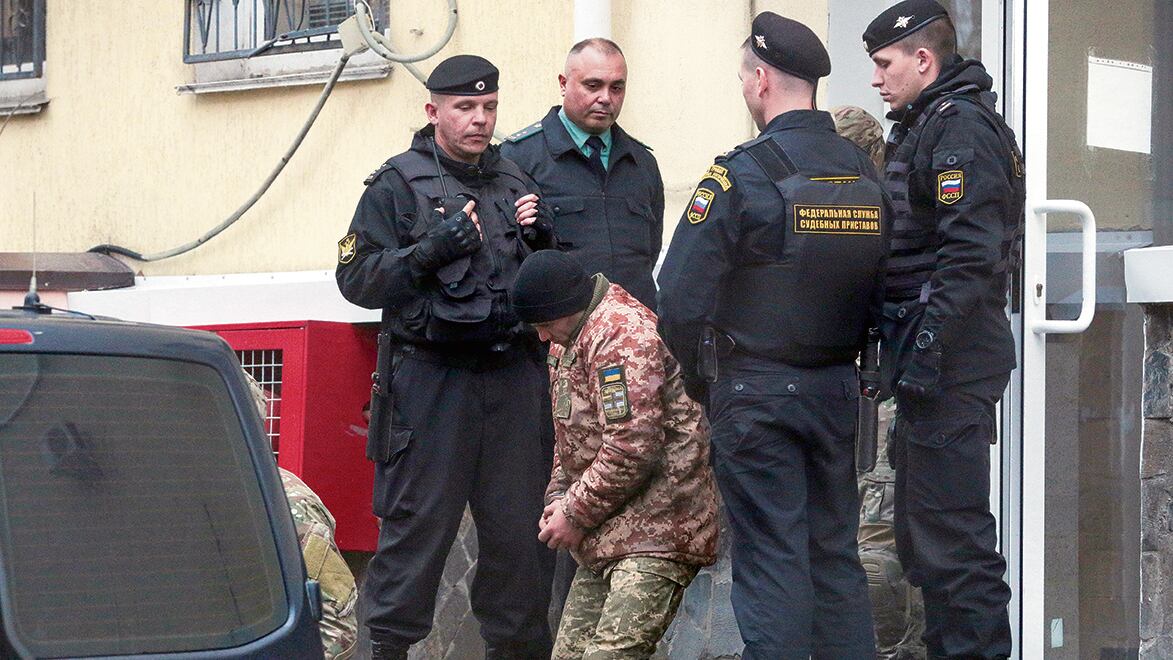 Un marino ucraniano es escoltado por militares rusos luego der ser detenido en Crimea.