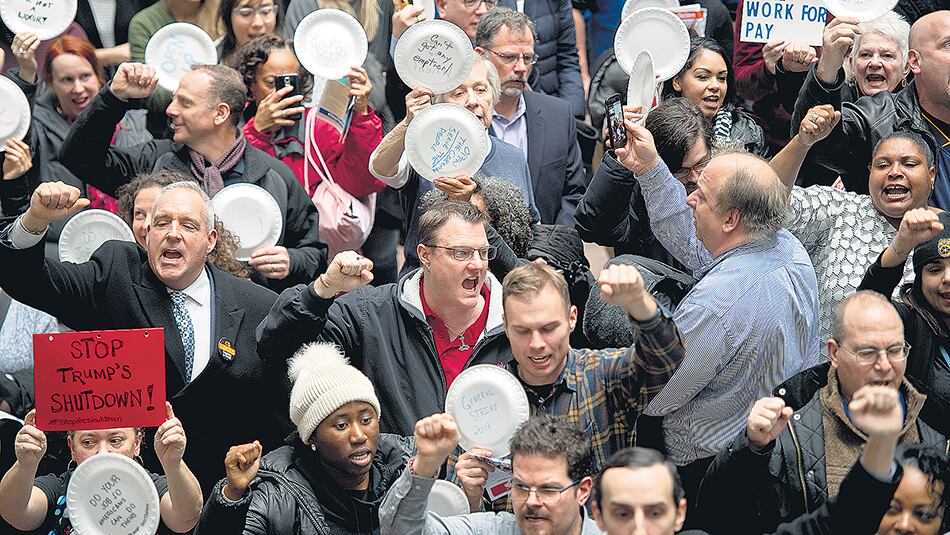 Empleados federales suspendidos protestan en Washington escribiendo consignas en platos descartables.