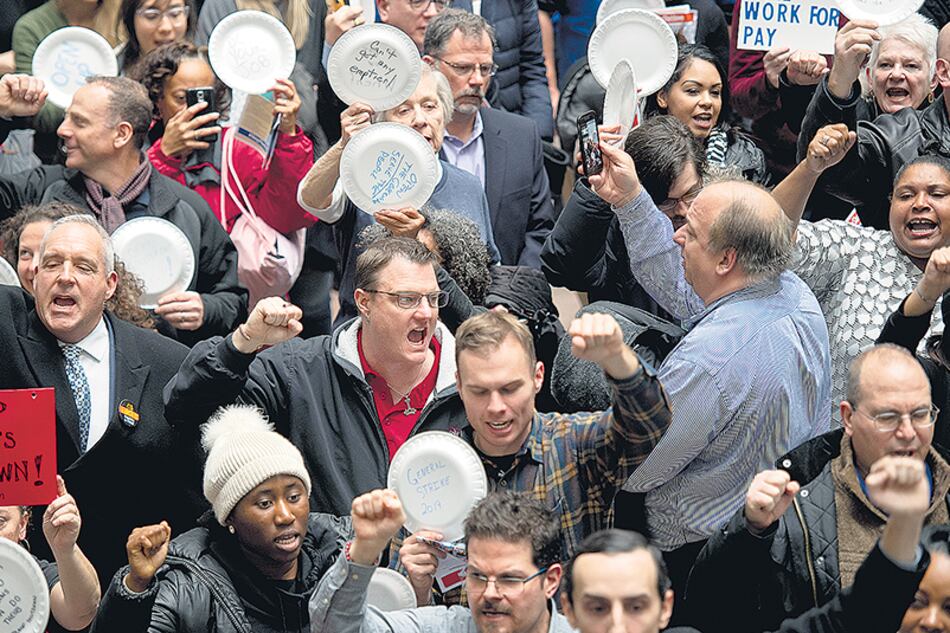 Empleados federales suspendidos protestan en Washington escribiendo consignas en platos descartables.