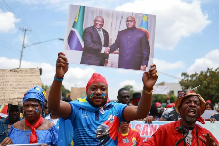 Miembros de la comunidad congoleña en Sudáfrica sostienen carteles y una pancarta con los rostros del presidente sudafricano y del presidente de la República Democrática del Congo (RDC). Imagen: Phill Magakoe/AFP