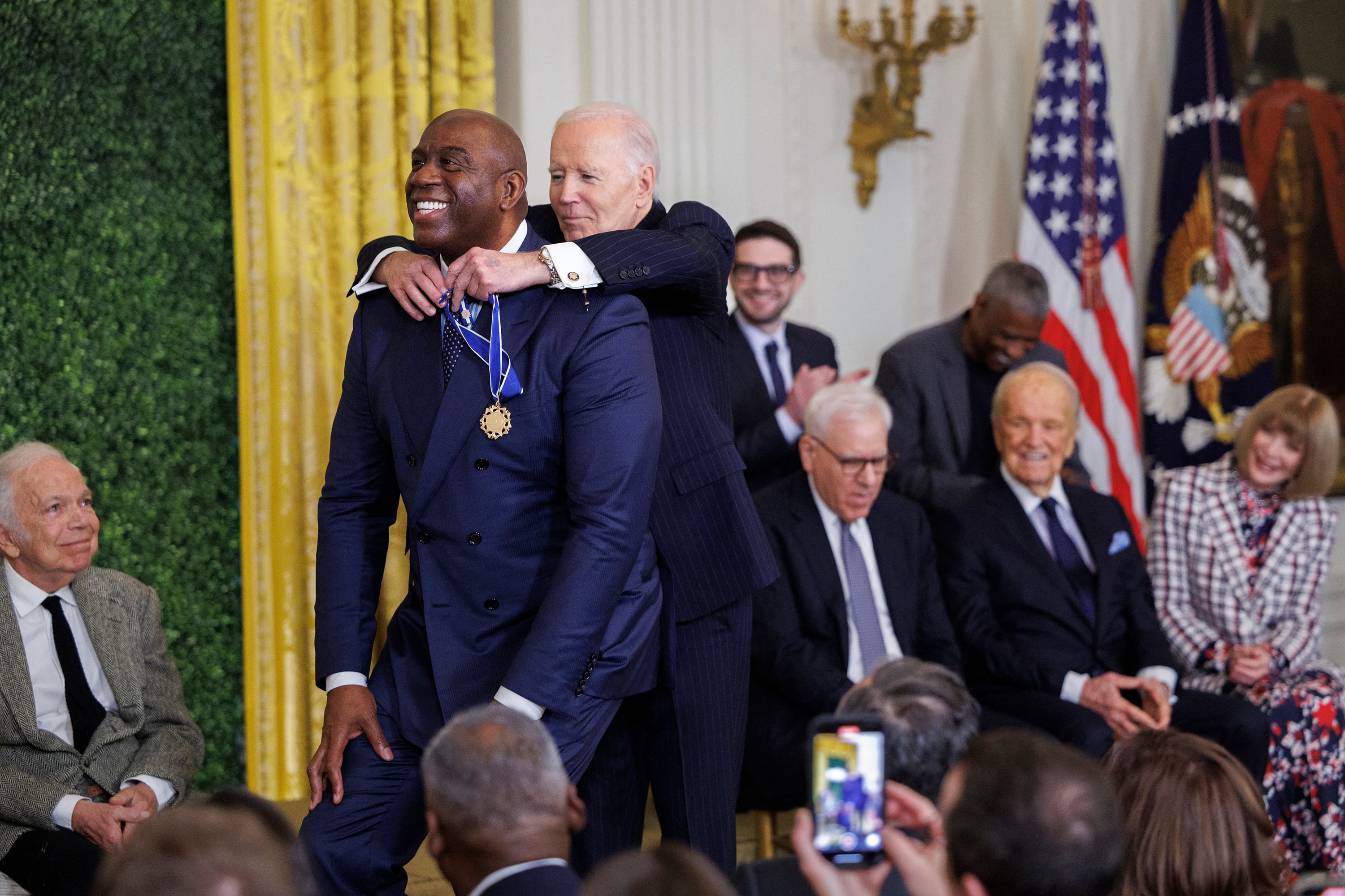 No, no es Messi, es Magic Johnson, que se agacha para ayudar a Biden. El rosarino no fue pero tendrá su medalla.