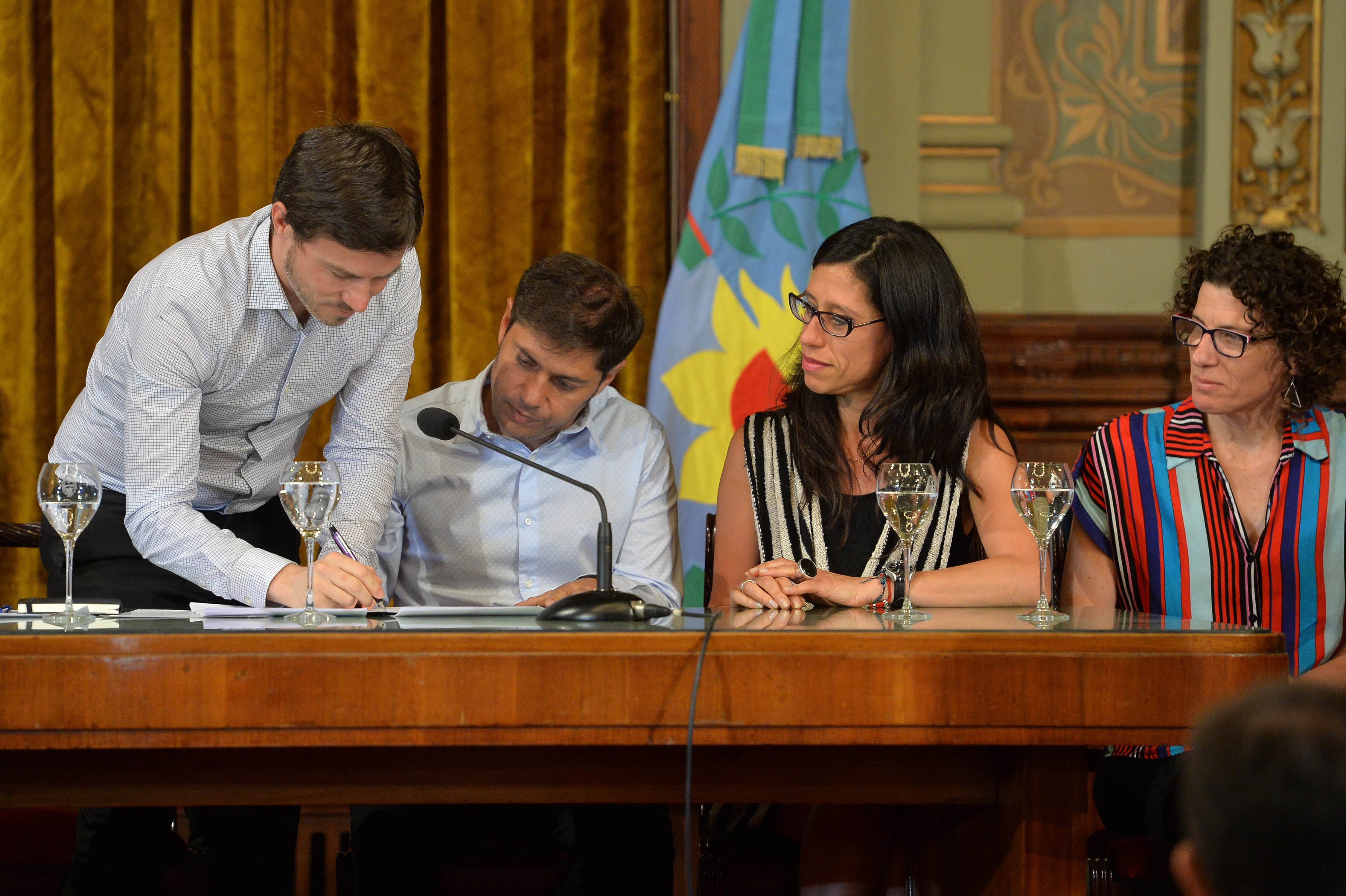 Costa firma ante la mirada de Kicillof y Paula Español.