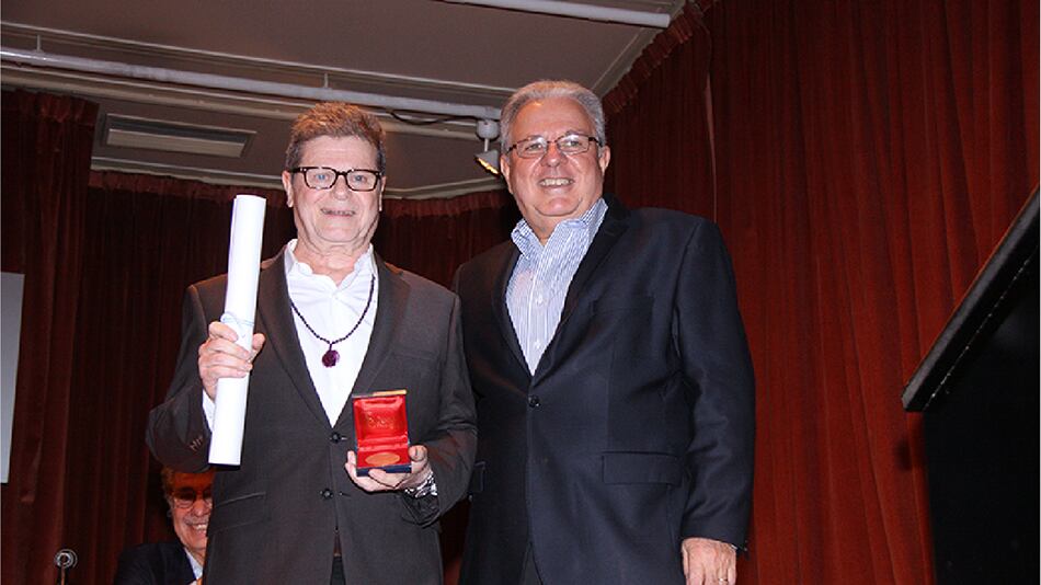 Gustavo Santaolalla recibe la distinción de manos del Rector de la Universidad de Buenos Aires, Alberto Barbieri.
