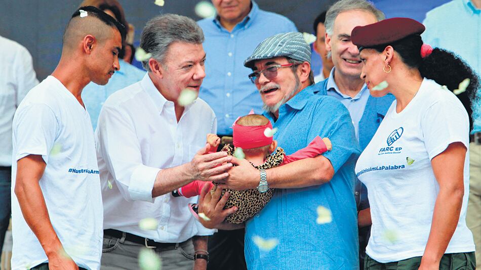 El presidente Santos saluda a una bebé que es sostenida por el máximo líder de las FARC, Londoño.