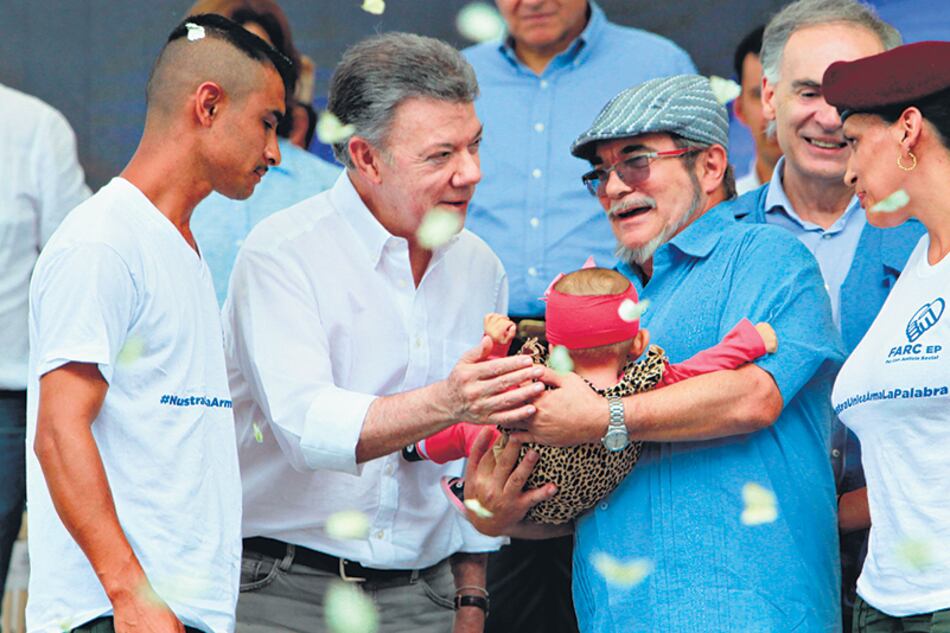 El presidente Santos saluda a una bebé que es sostenida por el máximo líder de las FARC, Londoño.